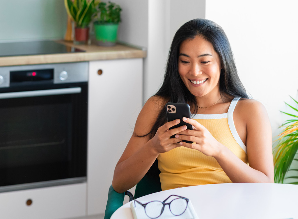 Person using phone behind kitchen table